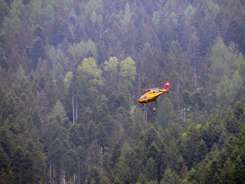 Elicottero del Soccorso Alpino in volo con verricello abbassato