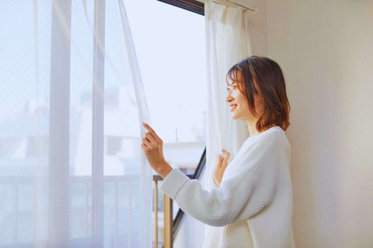 donna tende le tende termiche per ridurre i costi del riscaldamento